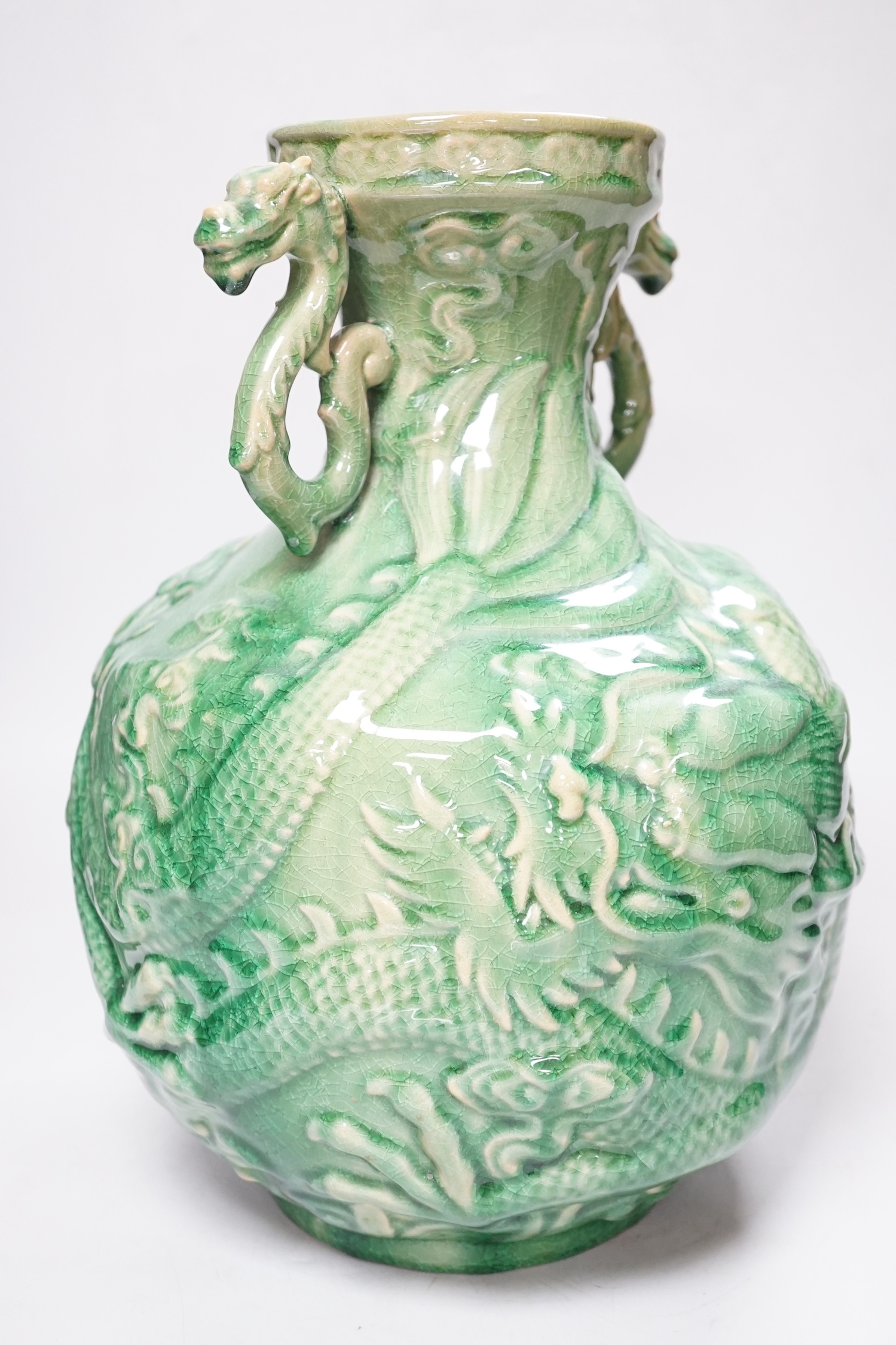 A Chinese green glazed vase with twin zoomorphic handles, decorated in relief with dragons, 35cm high